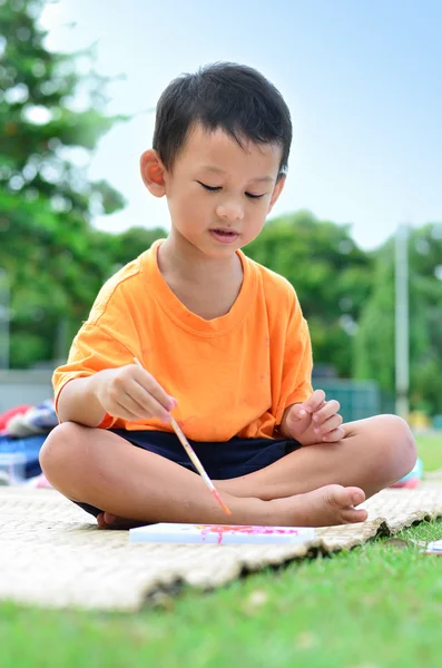 Going back to school : Boy drawing and painting over green grass — Stock Photo, Image