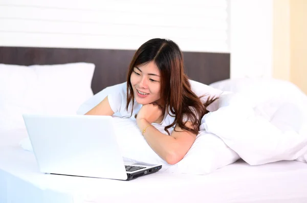 Asian teenage using laptop computer on bed — Stock Photo, Image