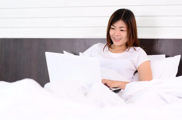 Asian teenage using laptop computer on bed — Stock Photo, Image