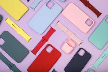 Renkli silikon telefon kılıfları, saat kayışı ve kulaklık için çanta. Hazır ol. Güncel teknoloji. Lavanta arka planında çeşitli kişisel aksesuarları kapatın. Düz yatıyordu