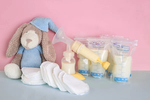 奶包和粉色蓝色背景的针织玩具 脱脂牛奶 奶瓶和乳房垫 乳腺泵 104 母乳育婴 冻结和储存 捐款额 — 图库照片