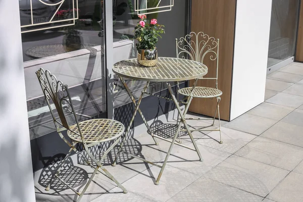 Forged chairs and a round table. Flowers on the table. Table for two. romantic concept