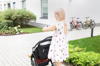a young mother checks the time while walking with a baby in a stroller walk with baby, street, selective focus
