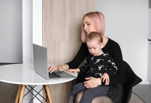 mother with a child in her arms works at a computer. Online work on maternity leave. Earning money for young mothers. Business mom. smart wife