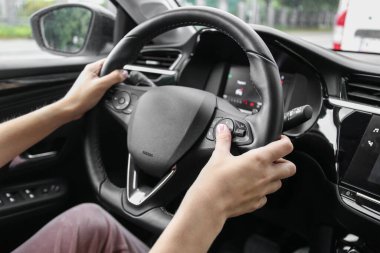 woman pressing buttons on multifunction steering wheel in car