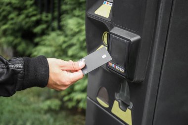 man hand pays for parking space at the parking meter by credit card
