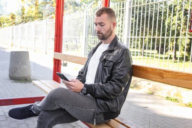 Otobüs durağında otobüs, tramvay, tramvay bekleyen bir adam. İşe, okula, üniversiteye toplu taşıma araçlarıyla gitmek. Geç kaldın. Yönlendirme zamanlaması.