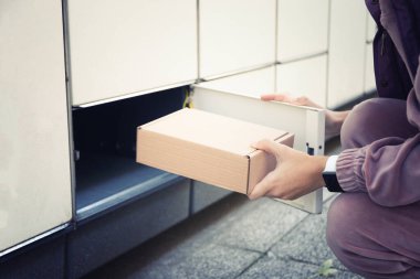 Kadın paketi self-servis posta terminalinden alıyor. Paket teslim makinesi.