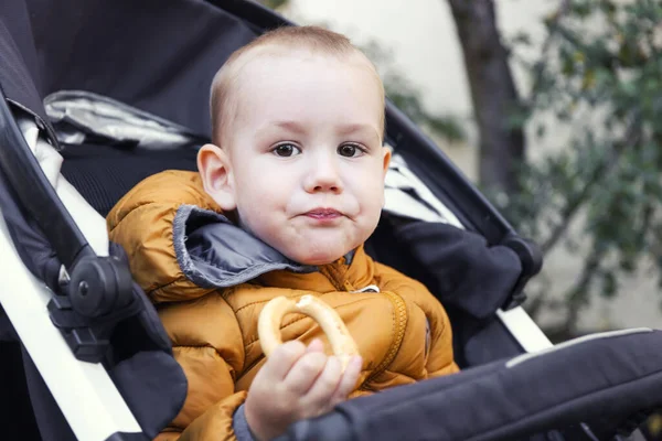 Child Eats Bun While Sitting Stroller — Zdjęcie stockowe