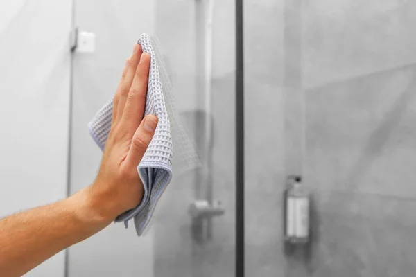 cleaning the house, washing the glass of the shower cabin. Girl cleaning her house