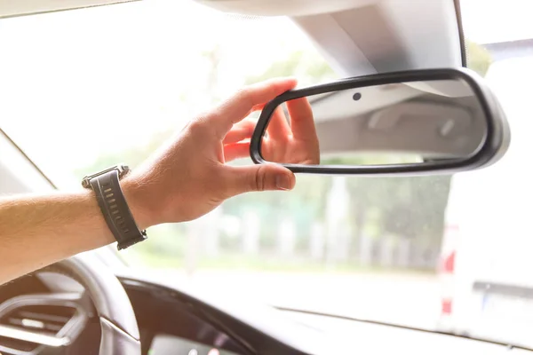 a man\'s hand corrects the rearview mirror in the car. Mirror with camera and sensors