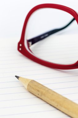 bir defter üstünde kırmızı gözlük