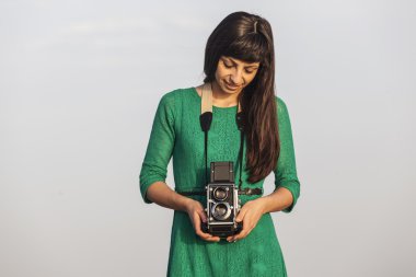 Deniz kenarında retro kamera ile esmer kız