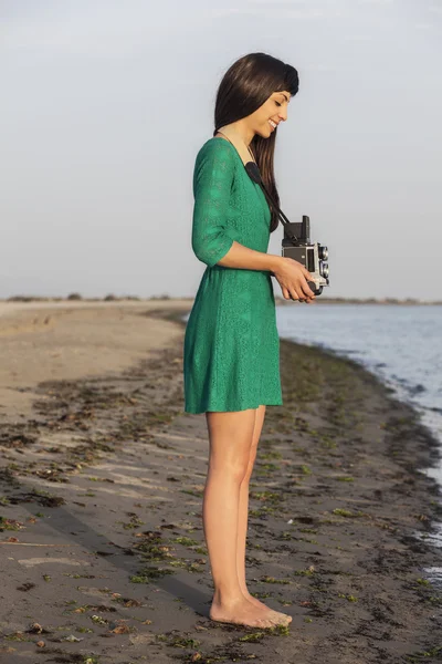 Brunette girl with retro camera by the sea — Stock Photo, Image