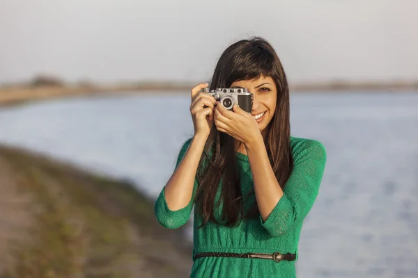 Brunette girl with retro camera by the sea — Stock Photo, Image