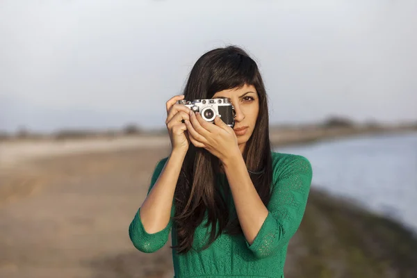 Brunette girl with retro camera by the sea — Stock Photo, Image