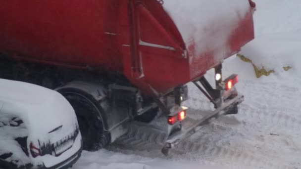 Sebuah truk sampah mogok di salju di atas es. Badai salju di musim dingin, roda berputar, close-up. — Stok Video