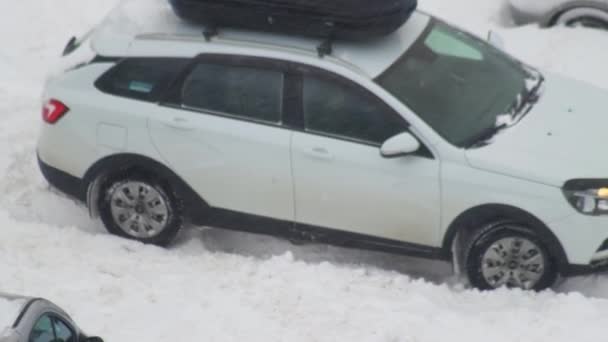 Пассажирская машина застряла в снегу. Колеса скользят по снегу на льду, крупным планом, вращаются на колесах — стоковое видео