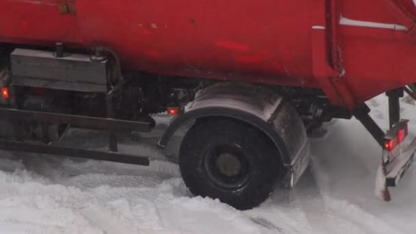 Un camión de basura se estancó en la nieve en el hielo. Tormenta de nieve en invierno, giro en la rueda, primer plano. — Vídeos de Stock