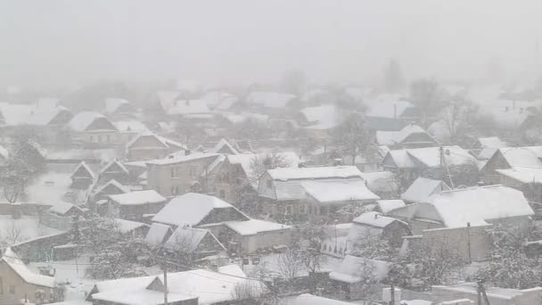 Sneeuwval in de winter tegen de achtergrond van het dorp en de dorpshuizen. Winterijzige dag. Kopieer ruimte voor tekst — Stockvideo