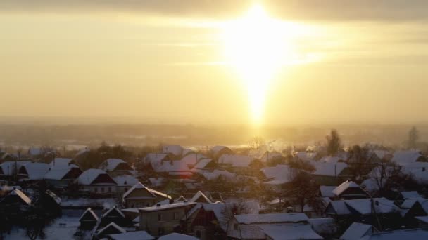 Orangefarbener Sonnenaufgang an einem frostigen Wintermorgen vor der Kulisse des Dorfes. Schöner Himmel und Schnee — Stockvideo