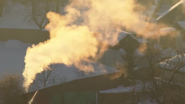 Помаранчевий дим виходить з димоходу в селі в морозний зимовий ранок. Світанок у селі, тло — стокове відео