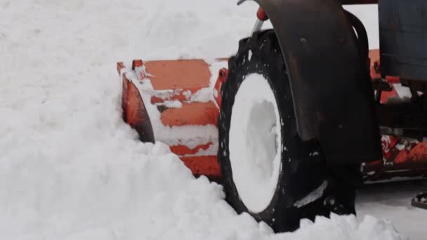 Трактор з жовтим відром видаляє сніг з вулиці взимку. Допомога в прибиранні доріг. Повільний рух — стокове відео