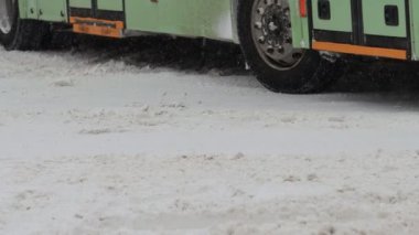 Kış. Şehir içi ulaşım otobüsü şehirde karlı bir yolda ilerliyor. Tekerlek lastiklerini yavaş çekimde kapatın. Kar yağışı. Trafik ve kar fırtınası için kötü hava koşulları. Trafik kazası tehlikesi