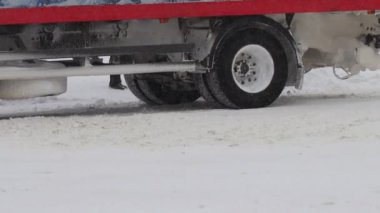 Kamyon arabası kışın karlı bir yolda gidiyor. Tekerlek lastiğini yavaş çekimde kapat. Trafik ve kar fırtınası için kötü hava koşulları. Yolculuk tehlikesi