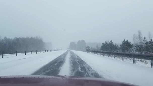 Вождение машины по проселочной дороге в снегу. Лед на дороге зимой. Опасность на дороге, плохая погода — стоковое видео