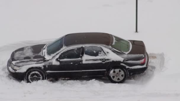 Osobní automobil uklouzne v zimě ve sněhu a pokusí se odjet. Kola uklouznou na ledu na zimních pneumatikách. Blizzard, detailní záběr — Stock video