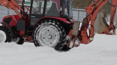 Sarı kovalı bir traktör kışın karları sokaktan kaldırır. Yol temizliği, endüstri