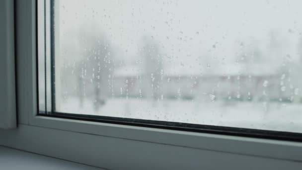 Drops on the glass of the home window. View from the window on the winter city and the road with cars, time-lapse. Rack focus — Stock Video