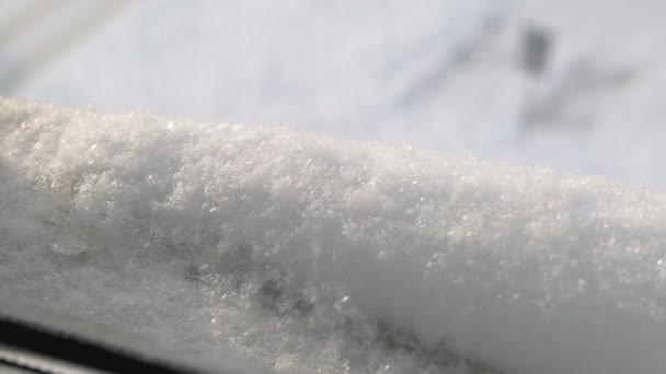 Flocos de neve caem na janela do parapeito no inverno. Boné de neve no peitoril da janela, fora — Vídeo de Stock