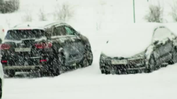 Coches cubiertos de nieve en un estacionamiento en la ciudad durante una nevada. Copos de nieve en el fondo de los coches, aparcado — Vídeos de Stock