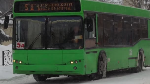 Χειμώνας. Μέσα Μαζικής Μεταφοράς Πόλη λεωφορείο είναι οδήγηση σε ένα χιονισμένο δρόμο στην πόλη. Χιονίζει σε αργή κίνηση. Κακές καιρικές συνθήκες για κίνηση, χιονοθύελλα. Κίνδυνος τροχαίων ατυχημάτων. Διασταύρωση — Αρχείο Βίντεο