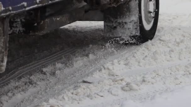Φορτηγό αυτοκίνητο είναι οδήγηση σε ένα χιονισμένο δρόμο το χειμώνα. Κοντινό πλάνο του ελαστικού τροχού σε αργή κίνηση. Κακές καιρικές συνθήκες για κίνηση, χιονοθύελλα. Κίνδυνος για ταξίδι — Αρχείο Βίντεο