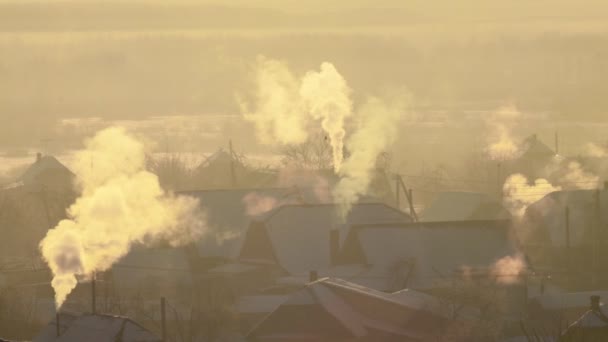 A fumaça de chaminés na aldeia sai no ar gelado no inverno. Nascer do sol laranja — Vídeo de Stock