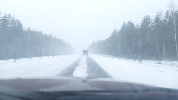 Conduire une voiture sur une route de campagne dans la neige. Glace sur la route en hiver. Danger sur la route, mauvais temps — Video