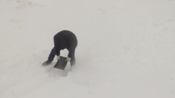 Ein Mann gräbt im Winter im Schneesturm mit einer Schaufel eine Straße frei. Kopierraum für Text — Stockvideo