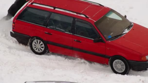 En personbil halkar i snön på vintern och försöker lämna. Hjulglidning på is på vinterdäck. Snöstorm, närbild — Stockvideo
