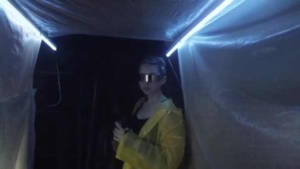 Futuro cyberpunk. Chica cyborg biónica femenina con pistola de revólver camina por el pasillo con película de plástico envoltura, parpadeos de iluminación, destellos de luz. Escena de ciencia ficción. Laboratorio científico secreto — Vídeos de Stock