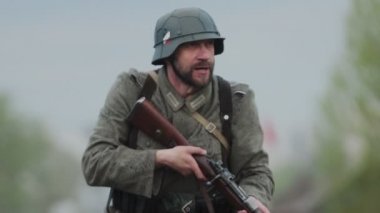 İkinci Dünya Savaşı sırasında Alman ordusunun Wehrmacht üniformalı sakallı askeri, 22 Haziran 1941 'de Sovyetler Birliği' nde işgalin yeniden inşası sırasında tüfeklere nişan alır, ateş eder ve yeniden doldurur. Yavaş çekim