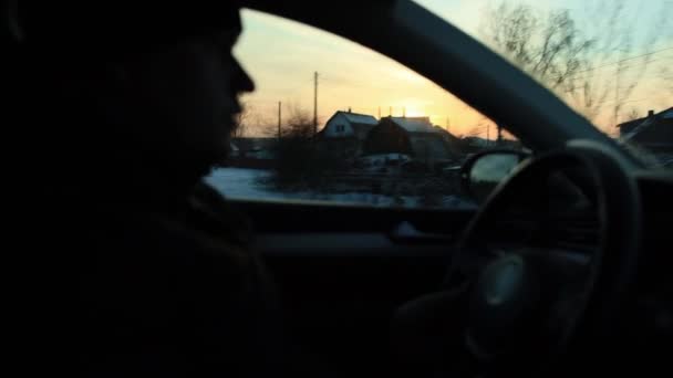 Conductor masculino que conduce un coche moderno en la noche en invierno con el telón de fondo de una puesta de sol soleada. Concepto de viaje y aventura en coche, autopista — Vídeos de Stock