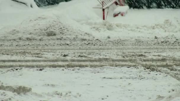 Машины едут по скользкой заснеженной дороге в городе зимой во время снегопада. Крупный план, дорожные реагенты, фон, открытый — стоковое видео
