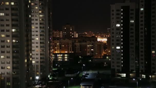 Nattstad i ljus. Ljus i fönstren i hus, ljus från bilstrålkastare och lampor på gatan — Stockvideo