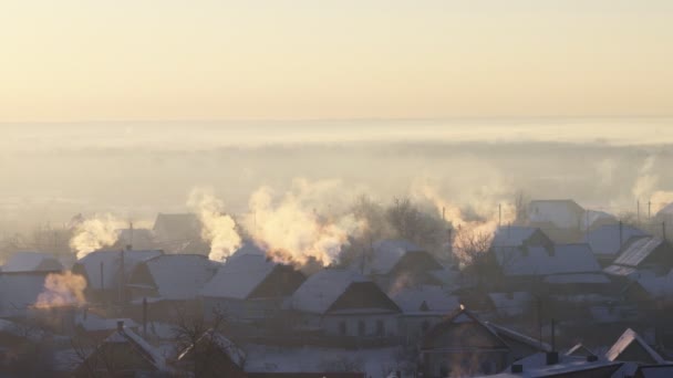 El humo de las chimeneas del pueblo sale al aire helado en invierno. Orange Sunrise. Copiar espacio para texto — Vídeo de stock