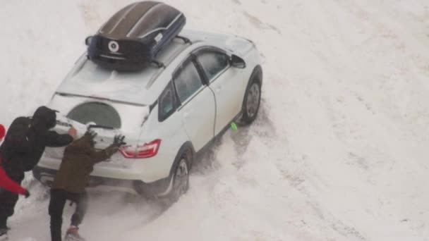 人々は冬に雪の中で止まっていた乗用車を押し出し — ストック動画