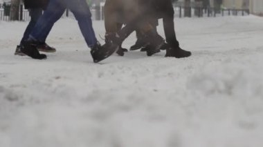 İnsanlar kışın kar yağışı sırasında yaya geçidinde yürürler. Kar taneleri yavaş çekimde düşüyor. Fırtına. Yaralanma riski var. Kötü hava koşulları, kar fırtınası. Noel ve Yeni Yıl