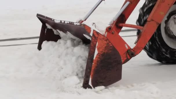 Трактор з жовтим відром видаляє сніг з вулиці взимку. Допомога в очищенні доріг, промисловість — стокове відео